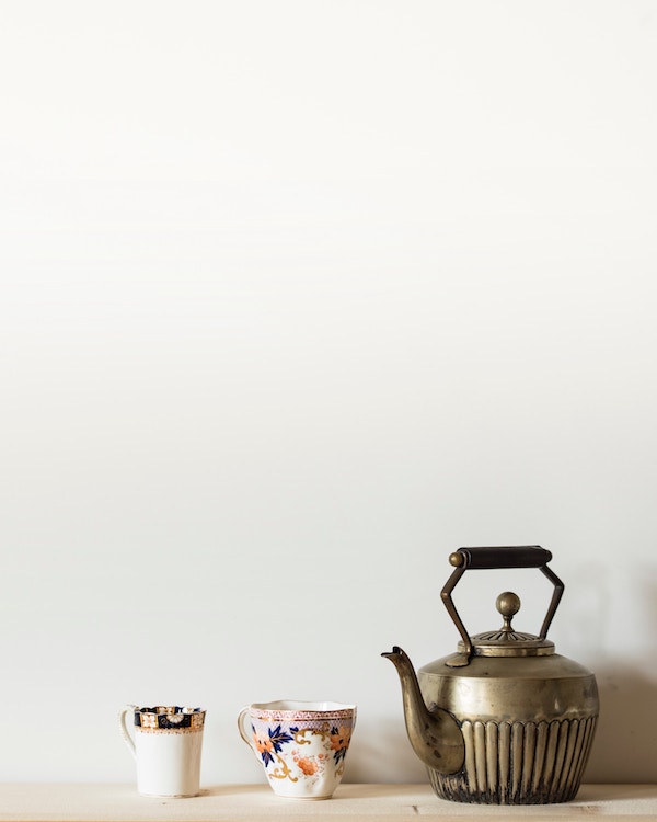 A zero waste teapot, cups, and saucers on a wooden table.