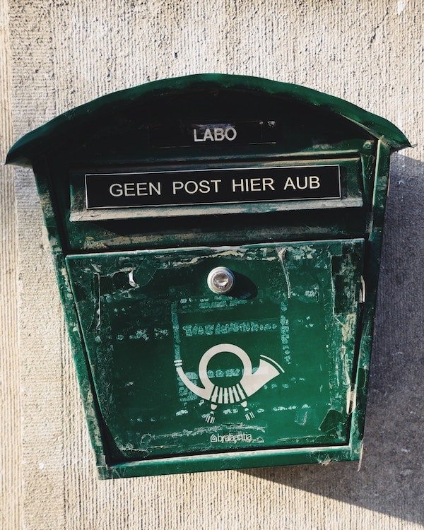 A green post box on the side of a building, used to deal with junk mail.