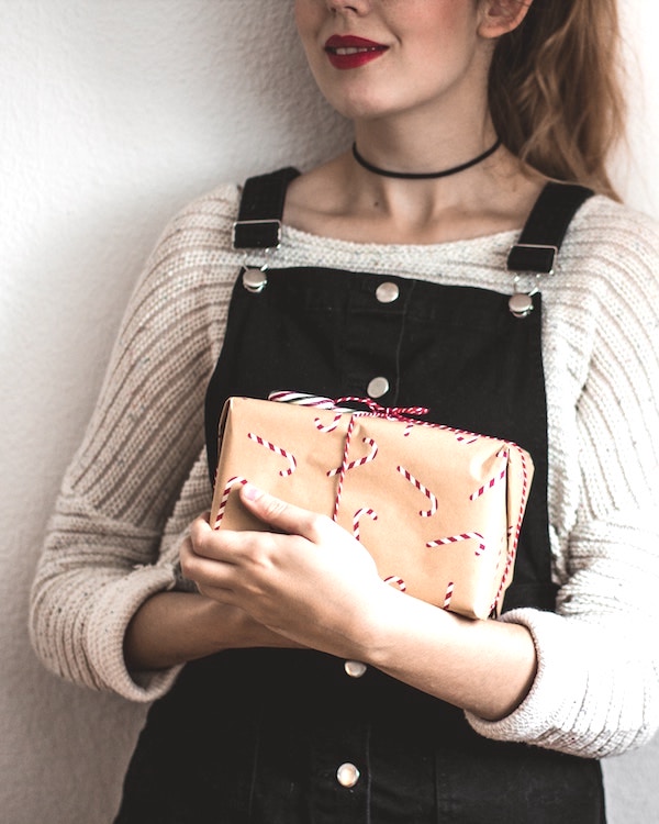 A woman in overalls holding a Christmas Wish List gift box.