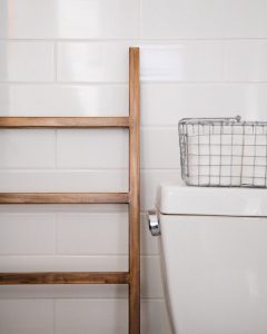 A wooden towel rack next to a toilet in a zero waste bathroom.