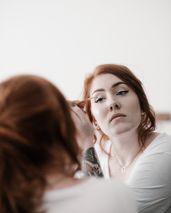 A woman getting her zero waste makeup done in front of a mirror.