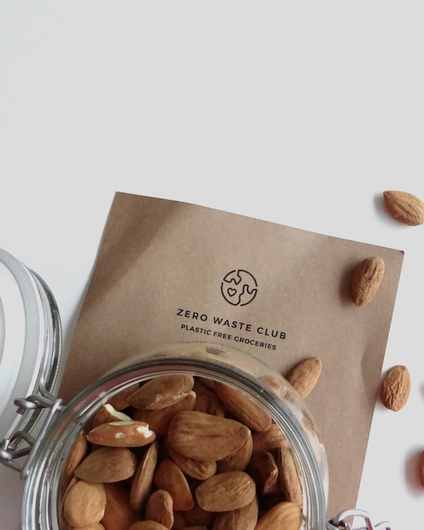 Almonds in a jar on top of a piece of paper, embodying a zero-waste grocery shopping style.