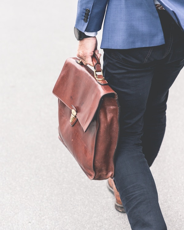 A man with a briefcase, contributing to our GDP, walking down the street.