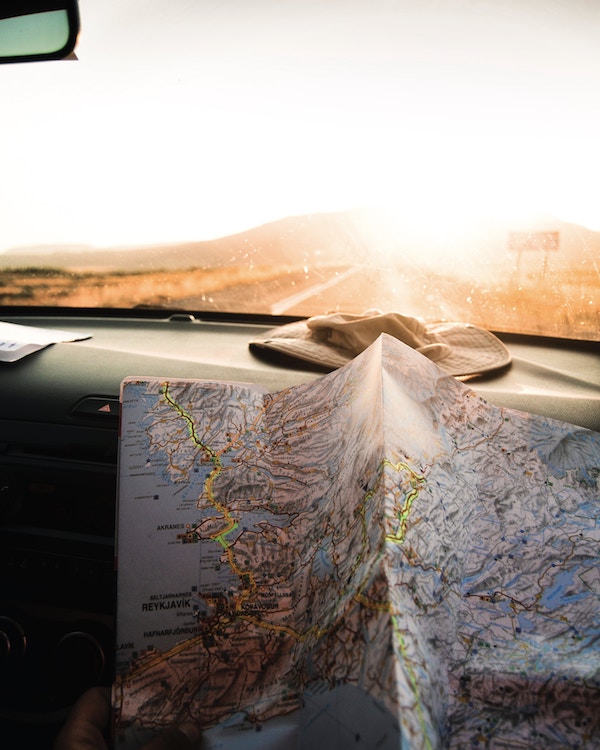 A person holding a map in a car, seeking sustainable travel tips.