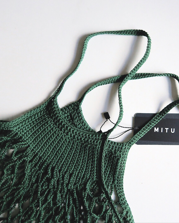 A green, Zero Waste crocheted bag with a tag on it.