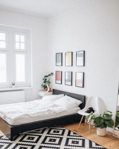 A bedroom cut back on energy waste with a black and white rug.