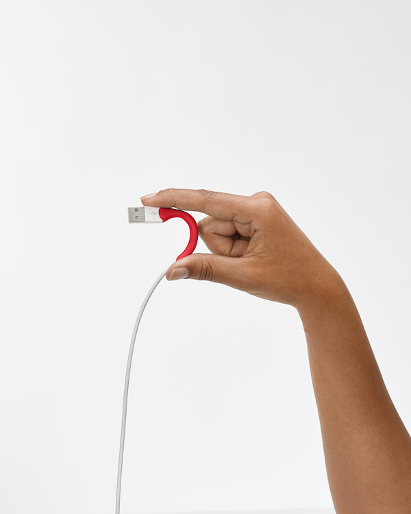 A person's hand holding a red USB cable for repair.