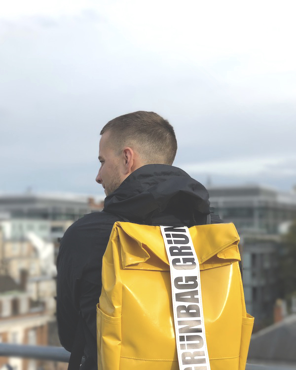 A man wearing an eco-friendly backpack looks out over a city.