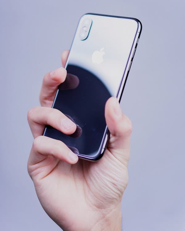 A person holding an iPhone while exploring a guide on sustainable technology, against a grey background.