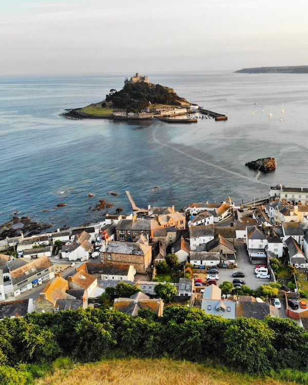 An aerial view of a town on a hill overlooking the ocean, a prime U.K. staycation destination.