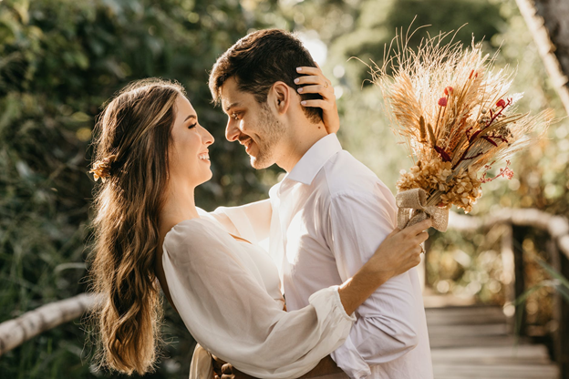 A couple embracing on a wooden walkway in a forest, celebrating their sustainable wedding.