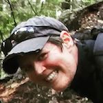 A woman with a backpack smiling in the woods, #5442.