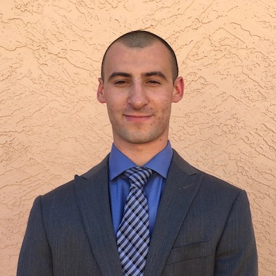 A man in a suit standing in front of a tan wall on a Single Page designed with Elementor.
