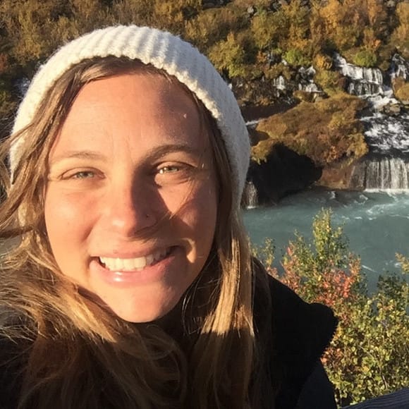 A woman smiling in front of a waterfall on a Single Page Elementor design.