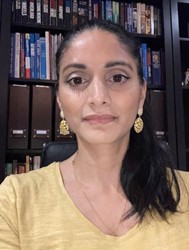 A woman in a yellow shirt is taking a selfie in front of a bookshelf.