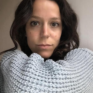 A woman wearing a blue knitted blanket on a Single Page created with Elementor.