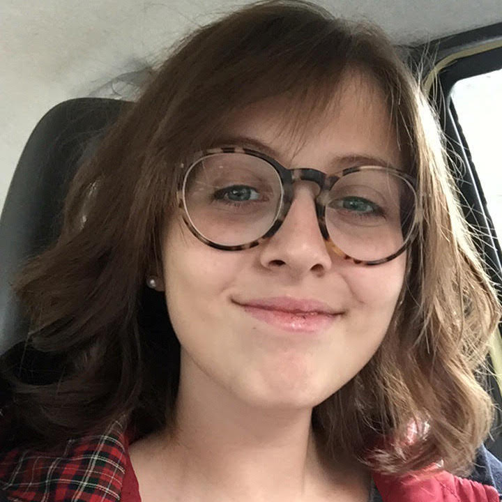 A woman wearing glasses and a plaid shirt in a car, captured on Single Page #5442 in Elementor.