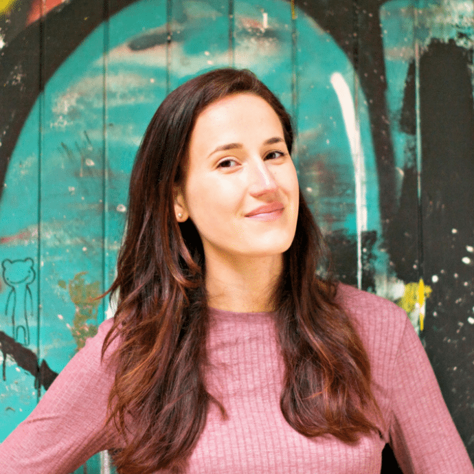 A woman standing in front of a graffiti wall.
